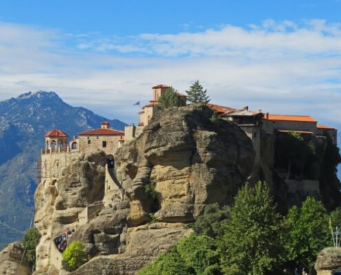 Eins der Meteora-Klöster in Griechenland balanciert auf einer Klippe vor einer Bergkulisse