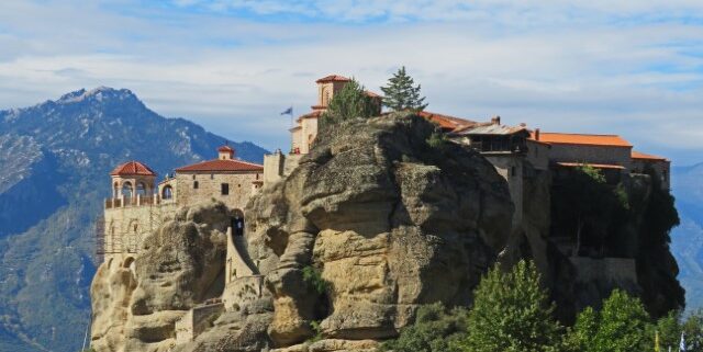 Eins der Meteora-Klöster in Griechenland balanciert auf einer Klippe vor einer Bergkulisse