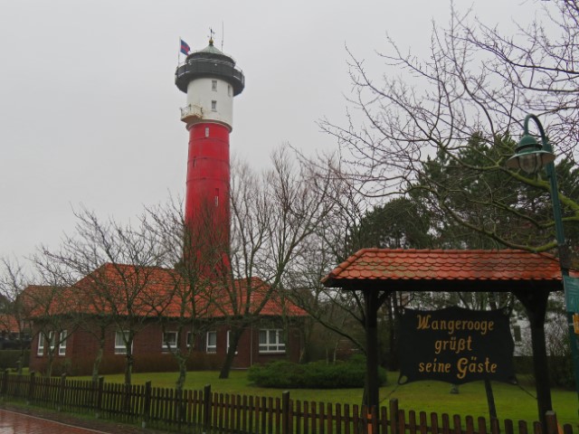 Roter Leuchtturm mit weißer Spitze umgeben von roten Häusern auf Wangerooge