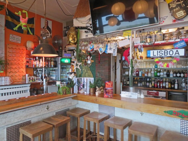 Inneres einer Strandbar auf Wangerooge mit vielen Flaschen und Autoschild "Lisboa"