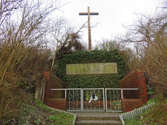 Denkmal mit großem Kreuz und grün bewachsenem Gebäude auf Wangerooge