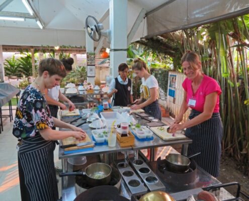 Mehrere Ausländerinnen an einem Tresen beim Kochen von Thai-Gerichten