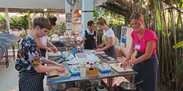 Mehrere Ausländerinnen an einem Tresen beim Kochen von Thai-Gerichten