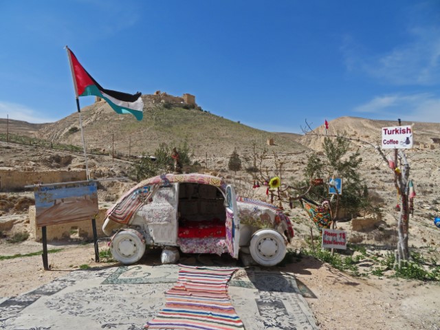 Altes Auto, das bunt verziert wurde und vor einer Bergkulisse steht mit der Aufschrift "das kleinste Hotel der Welt"