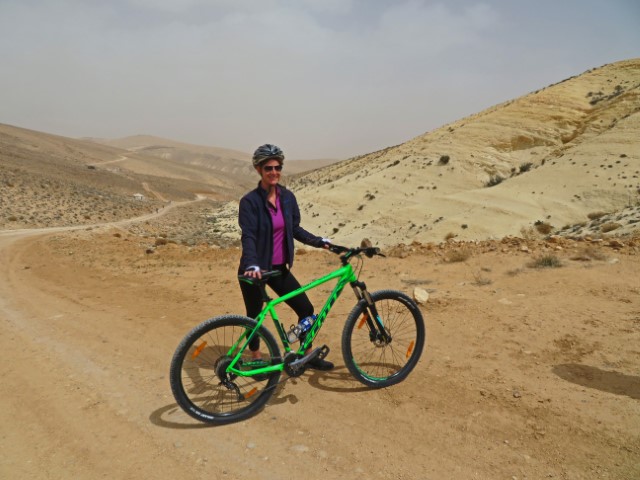 Junge Frau mit Helm und Mountainbike in der Wüstenlandschaft Jordaniens