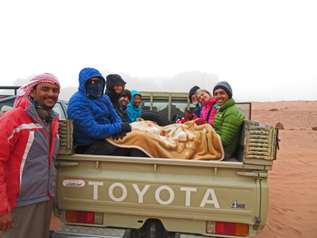 Mehere dick verpackte Touristen sitzen auf der Fläche eines Toyotas