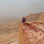 Junge Frau sitzt auf einer Klippe in der Wüste in Jordanien