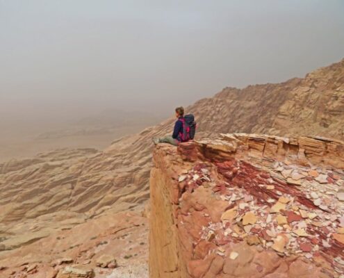 Junge Frau sitzt auf einer Klippe in der Wüste in Jordanien