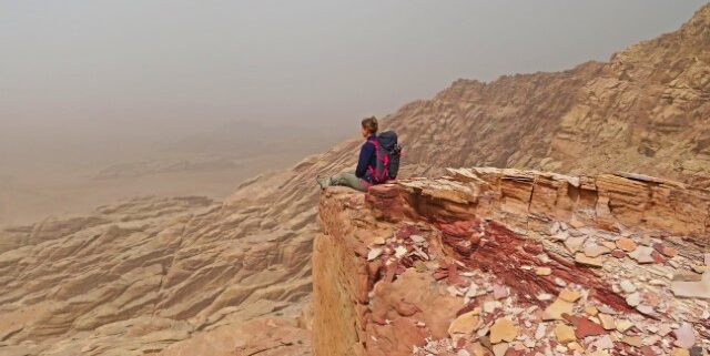 Junge Frau sitzt auf einer Klippe in der Wüste in Jordanien