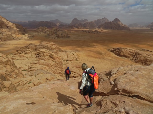 Wadi Rum mit seinen kargen Felsen badet in der Sonne, im Vordergrund Wanderer