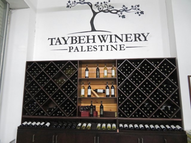 Schild der Taybeh Winery mit Weinflaschen darunter