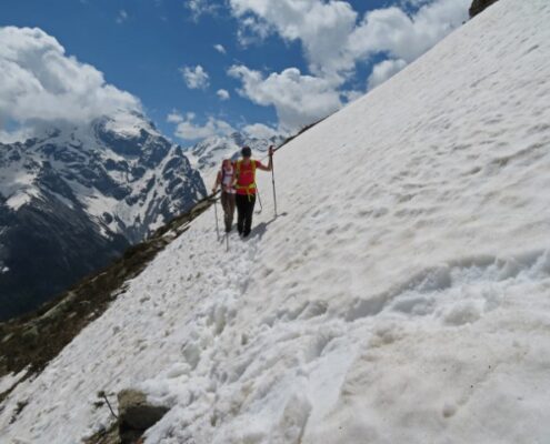 Zwei Wanderer stapßfen auf dem Ortler Höhenweg an einem verschneiten Abhang entlang