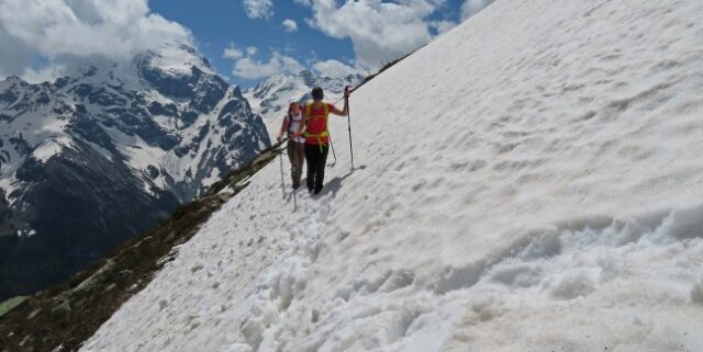 Zwei Wanderer stapßfen auf dem Ortler Höhenweg an einem verschneiten Abhang entlang