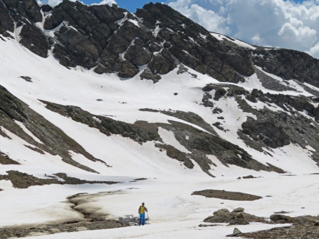 Winziger Wanderführer vor der mächtigen verschneiten Bergkulisse