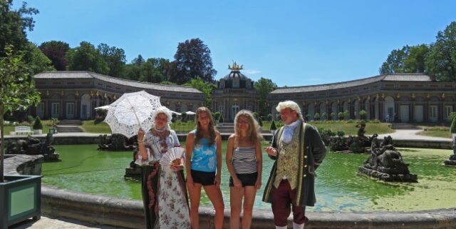 Zwei Mädels in Hotpants und zwei Schauspieler in historischen Kostümen vor dem Neuen Schloss in Bayreuth