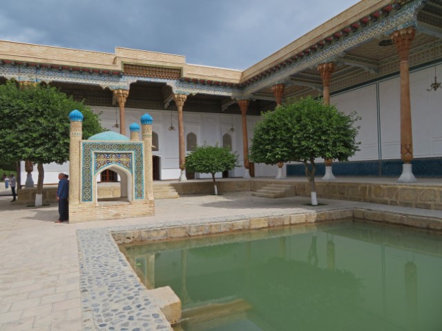 Grünes Wasserbecken vor den Bögen und Säulen eines Gebäudes im Mausoleum von Bakhauddin Naqshbandi