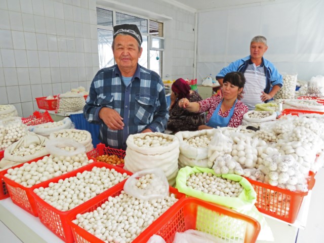 Auf dem Souk in Samarkand verkaufen ein älterer Mann und zwei Frauen Produkte wie Milchbällchen