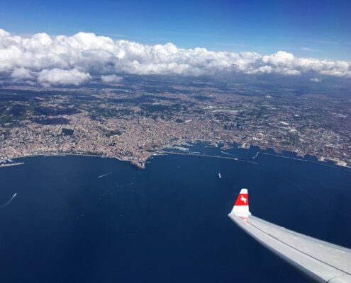 Flugzeug der Swiss Air fliegt über Wasser, im Hintergrund sieht man Land