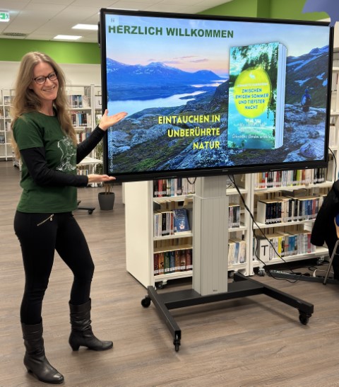 Autorin Bernadette Olderdissen mit Leinwand, darauf ihr Buch "Zwischen ewigem Sommer und tiefster Nacht" für einen Multimedia-Vortrag