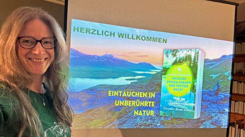 Autorin Bernadette Olderdissen bei einem Multimedia-Vortrag mit ihrem Buchcover auf der Leinwand